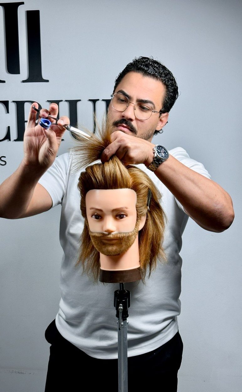 Johnathan Macedo cortando o cabelo de um manequim com tesoura